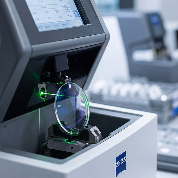 Óculos de armação dourada sob lensômetro no laboratório